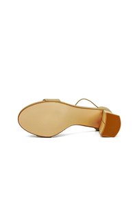 Sandalo con tacco alto beige, caratterizzato da una suola testurizzata, un tacco quadrato e sottili cinturini alla caviglia, con dettagli lisci lungo i bordi.