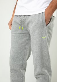Graue Sweatpants aus Baumwollmix, mit elastischem Bund, mehrfarbigen Kordelzügen und seitlichen Taschen; kleines Logo-Detail in der Nähe der Tasche.