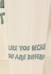 Light cream sweatshirt with a textured finish. Features green text reading, "I LIKE YOU BECAUSE YOU ARE DIFFERENT" on the front.