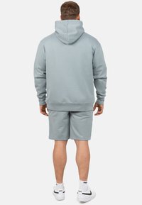 Lichtblauwe hoodie met een kangoeroezak, gecombineerd met bijpassende shorts. Soepele textuur, relaxte pasvorm en ribbelboorden en tailleband.