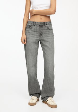 Grijze denim jeans met een relaxte pasvorm, voorzien van vijf zakken, een knoopsluiting en een lichte vervaging voor textuur. Gecombineerd met beige sneakers.