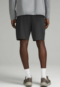 Pantaloni corti leggeri da uomo, di colore grigio scuro e dalla texture liscia, abbinati a scarpe da ginnastica grigie e calzini bianchi. Abbigliamento sportivo casual.