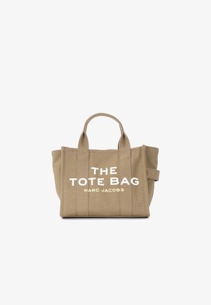 Beige canvas tote bag with two handles, vertical stitching, and white text "THE TOTE BAG MARC JACOBS" on the front.