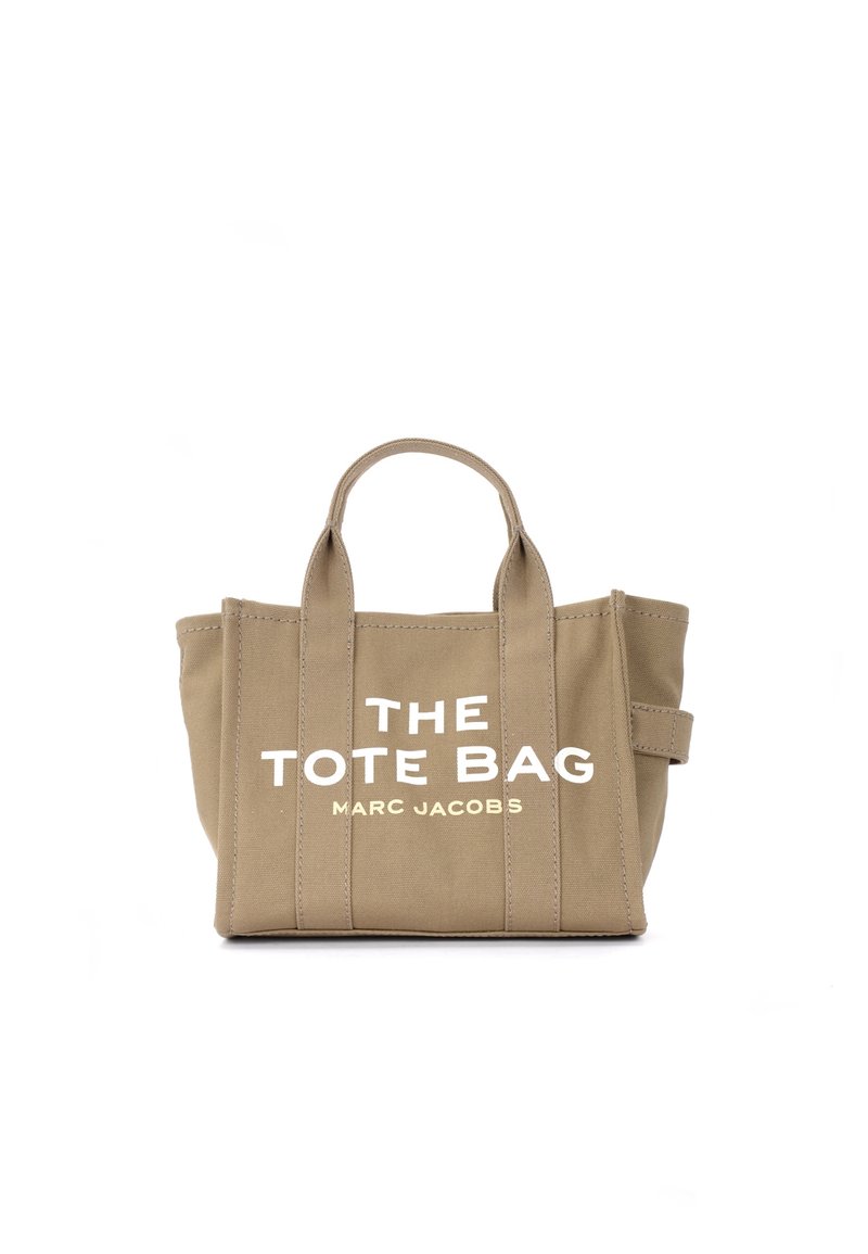 Saco tote de tela bege com duas alças, costura vertical e texto branco "THE TOTE BAG MARC JACOBS" na frente.