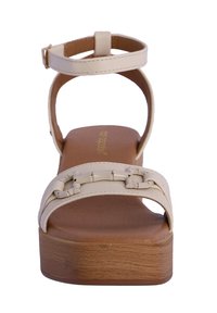 Sandalia de plataforma beige con parte superior de suave cuero sintético, correa para el tobillo ajustable y detalle decorativo de cadena en la correa delantera.