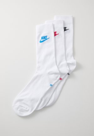 Balta Nike zeķu komplekts, kas ietver trīs pārus ar ribotu tekstūru. Katram pārim ir atšķirīga logotipa krāsa: zila, sarkana un melna.