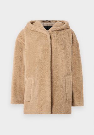 Manteau en fausse fourrure beige avec capuche, doté d'une coupe décontractée et de deux poches avant. La texture est douce et duveteuse, augmentant la chaleur.