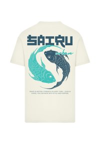 Cream-colored t-shirt featuring two stylized koi fish in teal and black. Text reads "SAIRU urban" with additional inspirational phrases below.