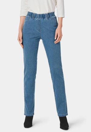 Jean en denim bleu clair avec une taille élastique, design à jambe droite et texture subtile. Porté avec des bottines noires et un haut blanc.