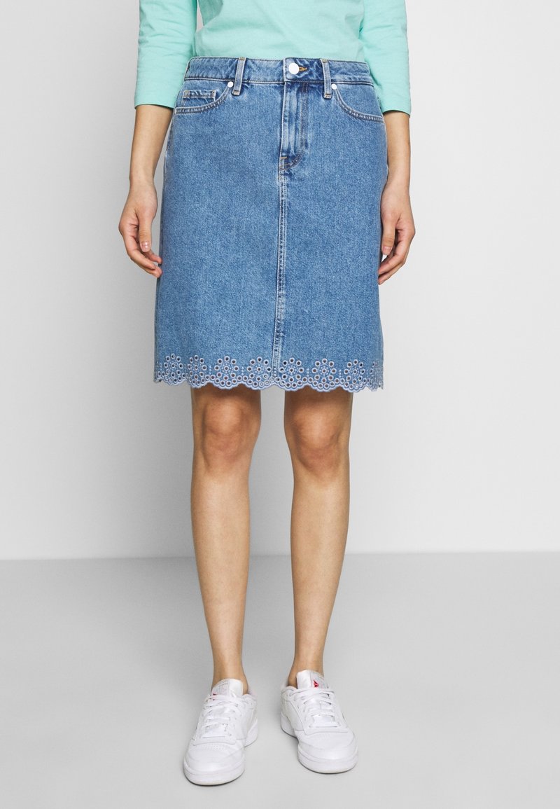 Džínová áčková sukně v světle modré barvě, střední délky s vykrojeným lemem, který má výšivku s otvorovými vzory. Pět kapes a přední zapínání na knoflíky.