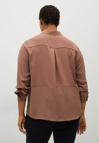 Brązowa, długorękawowa koszula z kołnierzykiem. Posiada wzór yoke i plisę z tyłu, wykonana z gładkiego, lekkiego materiału.