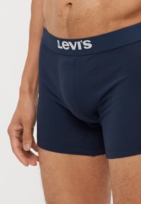 Marineblå bomullsboxere med hvit Levi's-logo på livlinjen. Har en tettsittende design og glatt tekstur.