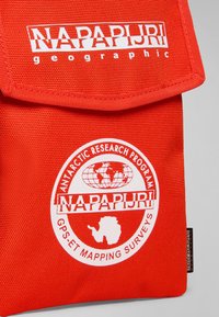 Röd tygväska med klaff. Har "Napapijri"-logotypen och en grafisk bild av forskning i Antarktis i vitt. Texturerat material, robust design.