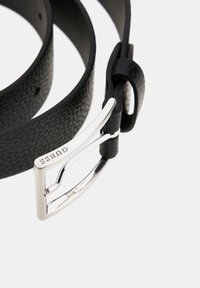 Schwarzer Leder-Gürtel mit strukturiertem Finish, ausgestattet mit einer silbernen Metall-Schnalle. Die Schnalle hat ein elegantes Design mit dem eingeprägten Markennamen.