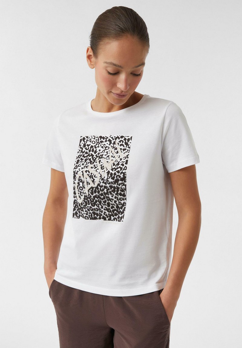 T-shirt en coton blanc avec un motif léopard noir et du texte. Manches courtes et encolure ronde classique. Texture douce.