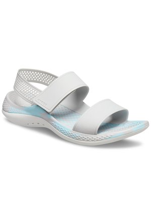 Witte sandalen met twee brede banden en een geperforeerd ontwerp. Voorzien van een gematteerde voetbed en lichtblauwe accenten op de zool.