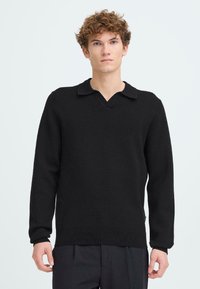 Čierny pletený sveter s výstrihom do V a golierom, s dlhými rukávmi a rebrovaným zakončením. Tkanina má hladký a jemný povrch.