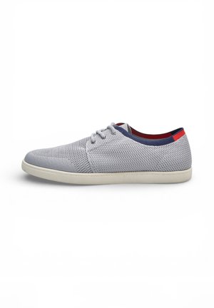 Scarpa casual in maglia grigio chiaro con suola bianca, bordo del colletto blu navy, linguetta sul tallone rossa e chiusura frontale con lacci su sfondo bianco.