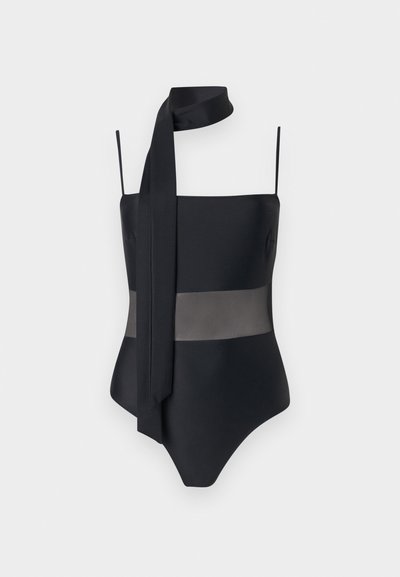 Maillot de bain une pièce noir avec fines bretelles, un panneau transparent au niveau du ventre et une longue écharpe attachée au cou.