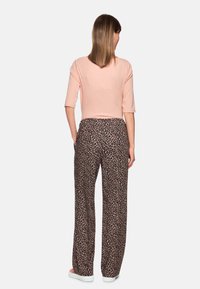 Light pink cropped top with three-quarter sleeves paired with loose-fitting black pants featuring a beige leopard print design.