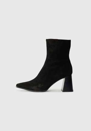Black suede ankle boot with a pointed toe, featuring a textured black block heel and a snug fit around the ankle. Smooth surface texture.