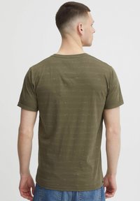 Olivegrünes T-Shirt mit kurzen Ärmeln aus weichem Stoff, das horizontale Texturmuster aufweist. Rundhalsausschnitt und gerader Saum, mit minimaler Ausstattung.