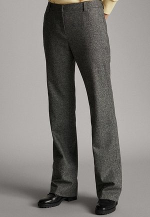 Mørkegrå uldbukser med lige skæring, båret med sorte læderstøvler og en beige sweater, vist fra talje til fødder.