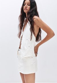 Witte denim jurk met een diepe V-hals, knoopsluiting en zijzakken; gladde textuur met een minimalistisch ontwerp en zonder prints.