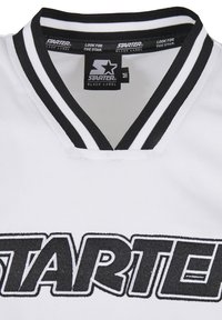 Hvid sportstrøje med et sort broderet "STARTER"-logo. Har en sort-hvid stribet V-halskrave og et struktureret stof.