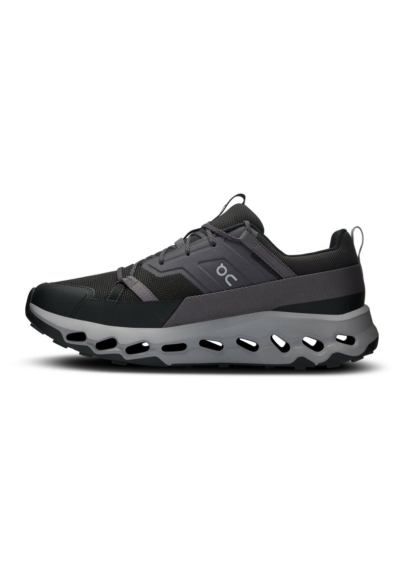 Baskets de sport noires et grises avec un dessus texturé, une semelle courbée et des découpes pour la ventilation. Comprend des lacets et un logo sur le côté.