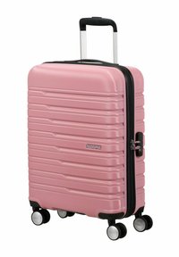 Valigia rigida rosa con scanalature diagonali, cerniera nera, manico retrattile e quattro ruote multidirezionali per una facile mobilità.