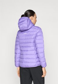 Giacca a vento viola con cappuccio, caratterizzata da un design trapuntato, texture liscia e logo sul retro. Le maniche sono aderenti e la giacca è di lunghezza media.