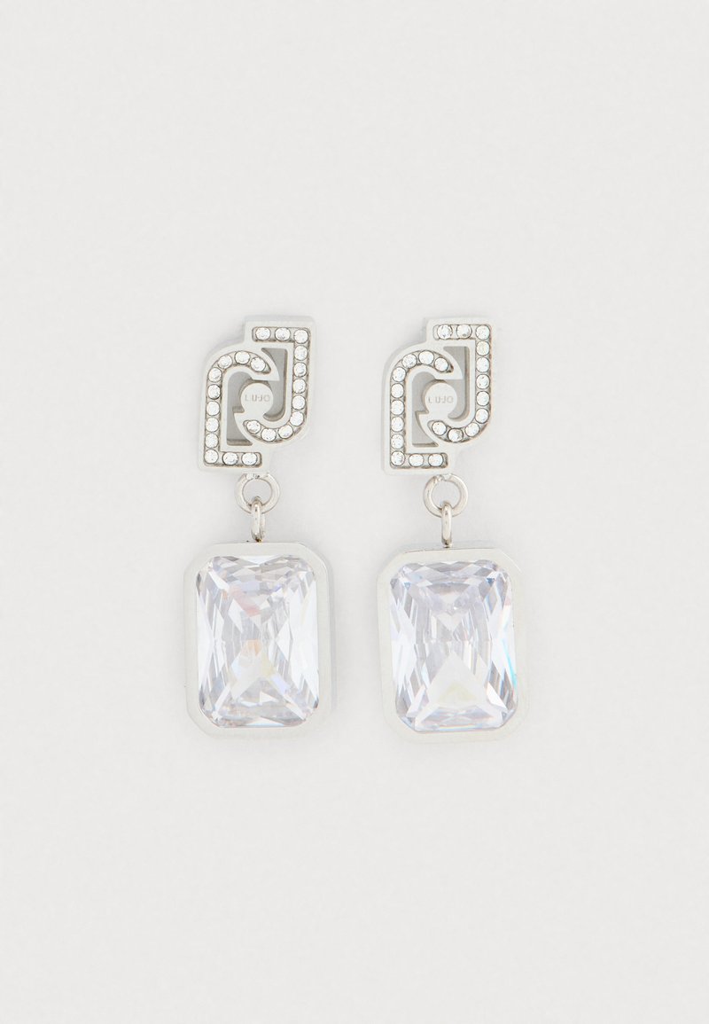 Sudraba toņa pilienveida auskari ar savienotiem ģeometriskiem studiem, rotātiem ar mazām kristālēm un lieliem taisnstūra caurspīdīgiem akmeņiem ar facetes.