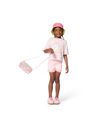 Vaaleanpunainen t-paita, jossa yksisarviskuvio, vaaleanpunaiset shortsit, vaaleanpunaiset lenkkarit ja keltavihreä lierihattu. Kädessä koristeellinen olkalaukku.