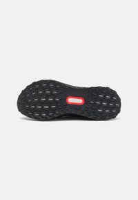 Semelle extérieure en caoutchouc noir avec un motif de crampons texturé, présentant un accent rouge et un détail de marque. Conçu pour l'adhérence et la durabilité.