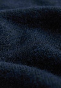 Tessuto navy con trama che mostra un materiale morbido e peloso con profondità variabili, creando un motivo ondulato sulla superficie.