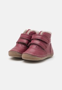 Un paio di stivali rosa per bambini con foderatura in pile beige e doppie chiusure in Velcro, suole in gomma marrone su sfondo bianco.