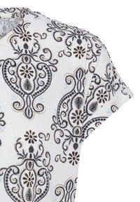 Biely materiál s čiernymi a béžovými zložitými kvetinovými a paisley vzormi na tričku s krátkym rukávom a výstrihom s výrezom.