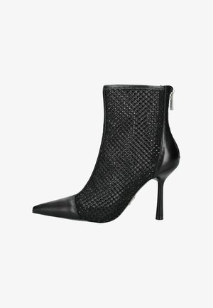 Bottine noire à talons hauts avec bout pointu, présentant un dessus en maille tissée et des accents en cuir lisse. Fermeture éclair sur le côté.