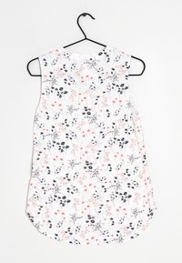 Sleeveless top hanging on a black hook, featuring a white background with floral patterns in red, black, and gray hues. Rounded hem.
