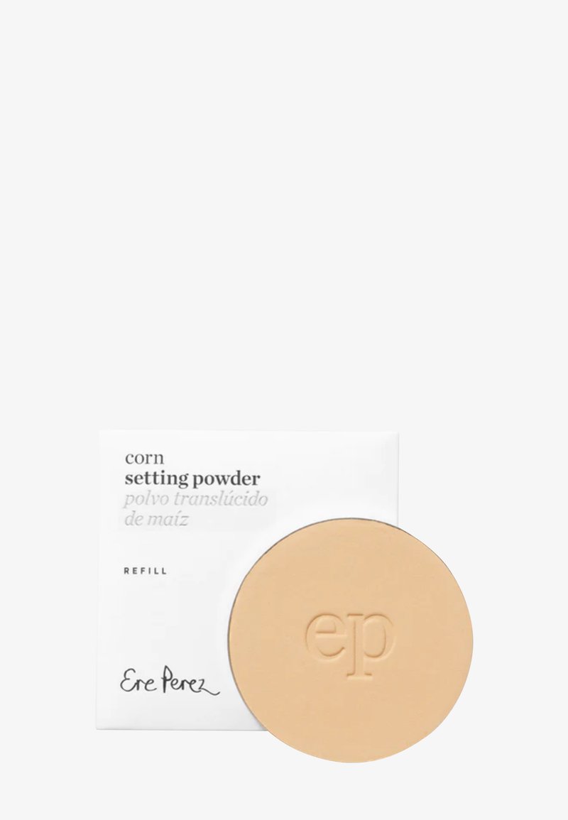Poudre fixante à base de maïs dans un boîtier rond beige. Le produit porte un logo "ep" en relief. Une boîte blanche présente un texte noir détaillant le produit.