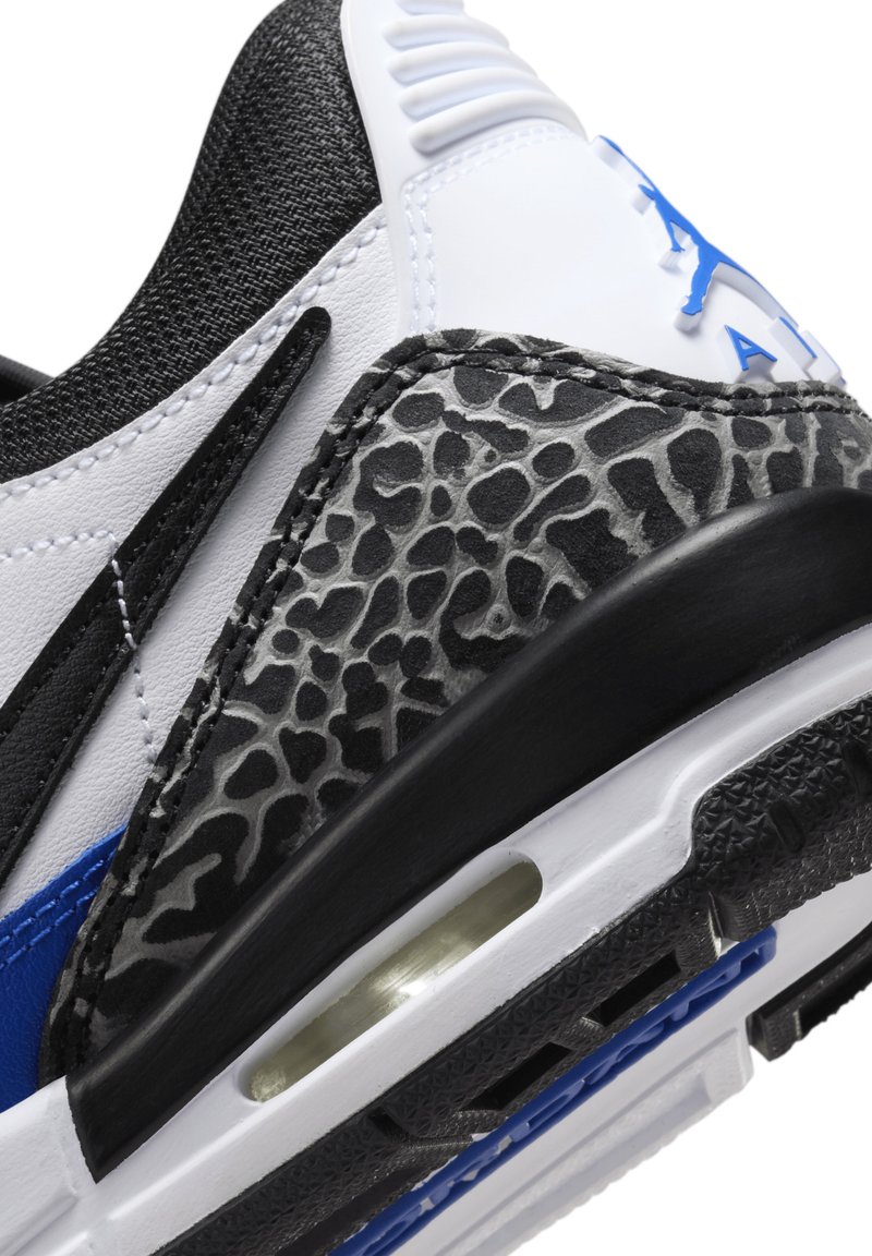 Sneaker w kolorach czarnym, białym i niebieskim. Wykonany z syntetycznego materiału z teksturowanym szarym wzorem przypominającym skórę słonia oraz widoczną jednostką poduszki powietrznej.