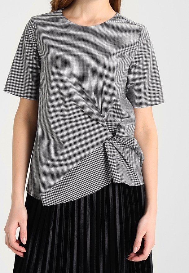 Top a maniche corte in motivo check nero e bianco, con dettaglio frontale annodato e vestibilità rilassata. Tessuto testurizzato, design casual.