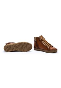 Scarpe in pelle marrone a metà altezza con suola in gomma testurizzata, dettagli in metallo dorato e un design di lacci intricato; dotate di cerniera laterale.