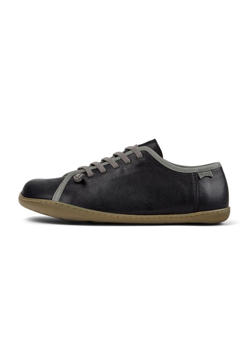 Scarpe in pelle nera con accenti grigi, caratterizzate da un profilo basso e un design con lacci, esposte su uno sfondo bianco.