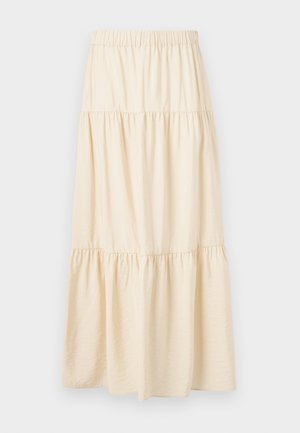 Bēšs daudzpakāpju svārks ar elastīgu jostasvietu un trim savāktām daļām, kas veido plūstošu, vaļēju piegriezumu.