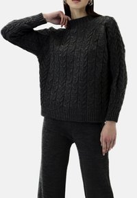 Dunkelgrauer, strickpullover mit Norwegermuster, hohem Kragen, gerippten Bündchen und lockerem Schnitt, kombiniert mit passenden Hosen aus ähnlich strukturiertem Stoff.