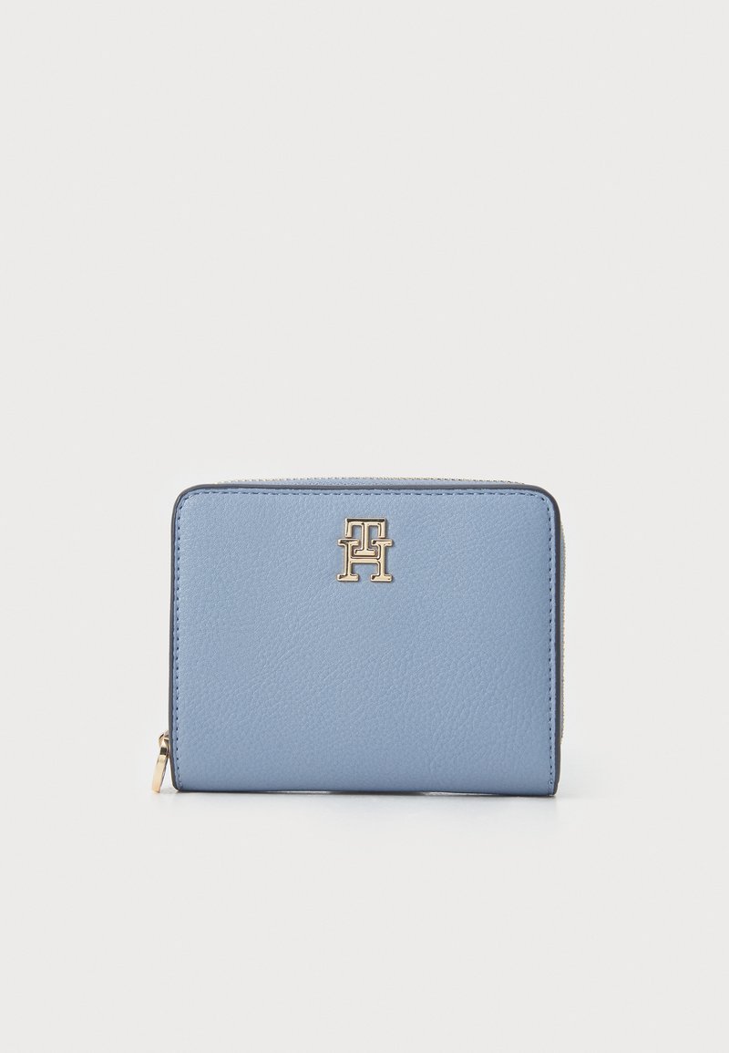 Light blue leather wallet with a textured finish, featuring a gold hardware logo and a zip closure along the edge. Compact rectangular design.