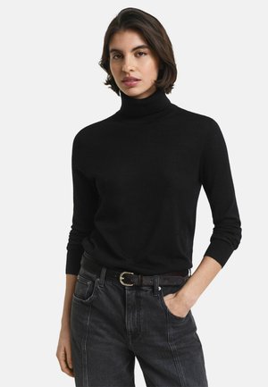 Zwarte coltrui, geribbelde textuur, slim fit, ronde hals. Gecombineerd met donkere spijkerbroek, geaccentueerd met een bruine riem met gouden gesp.