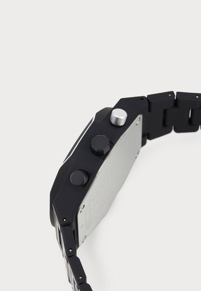 Orologio rettangolare nero con finitura opaca. Presenta pulsanti argentati, un retro in metallo e un bracciale a maglie realizzato in materiale nero.